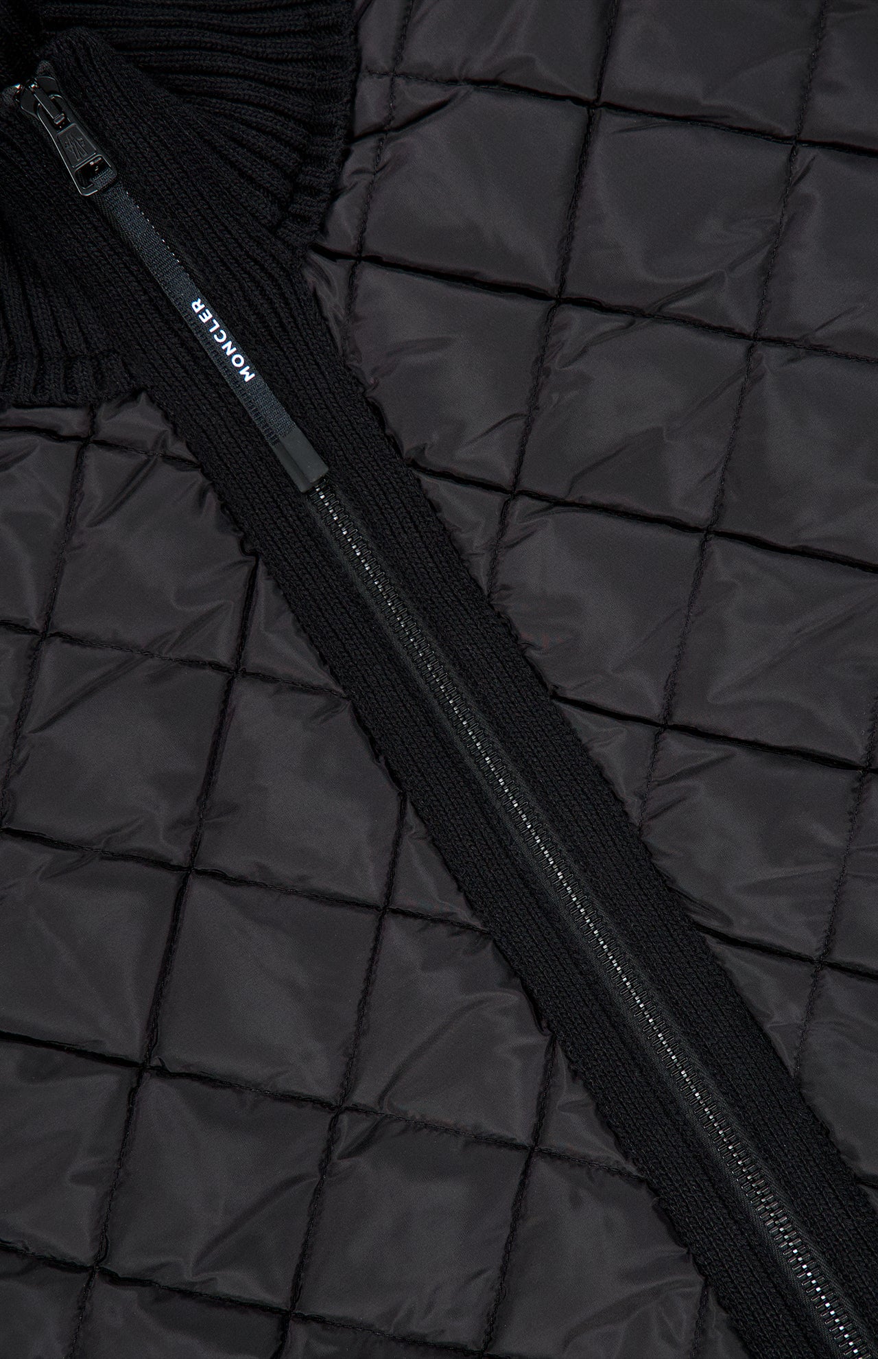 Close-up of a black Moncler Puffer Zipped Up Jacket with a diamond quilted pattern, zippered closure, and ribbed collar.