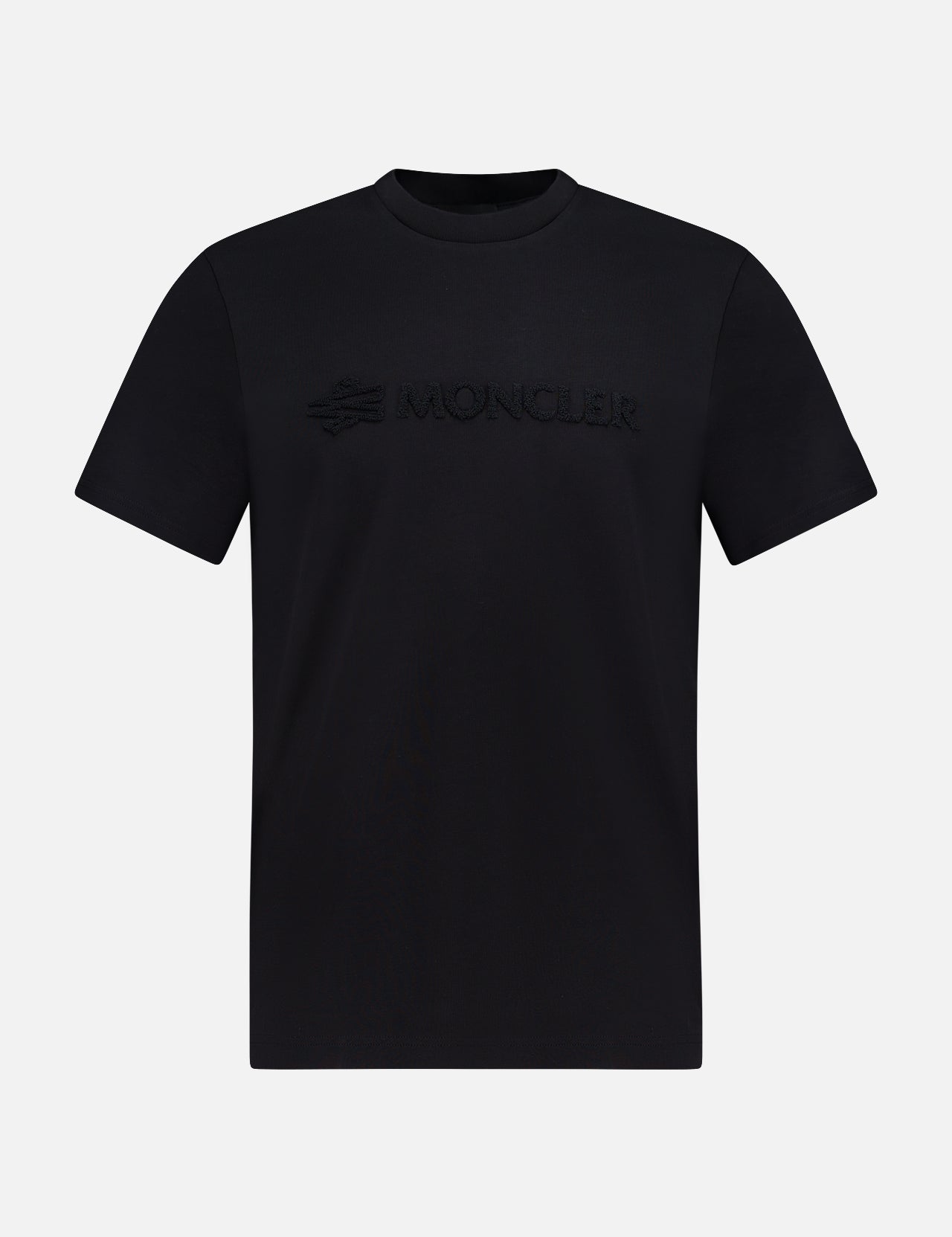 The MONCLER Short Sleeve Logo T-Shirt is a plain black tee with a 3D embossed MONCLER logo across the chest, shown on a white background—a stylish choice from the designer brand.