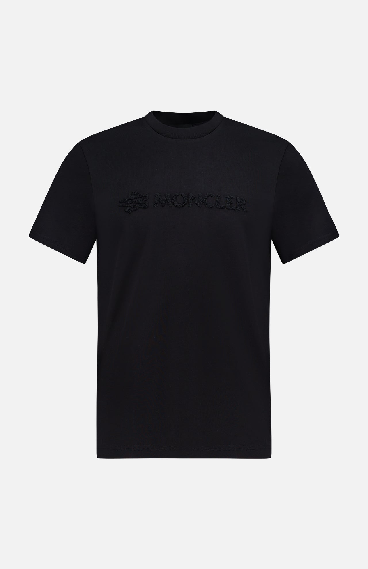 The MONCLER Short Sleeve Logo T-Shirt is a plain black tee with a 3D embossed MONCLER logo across the chest, shown on a white background—a stylish choice from the designer brand.