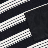 Close-up of the MONCLER Striped Long Sleeve T-Shirt, featuring black, white, and gray horizontal stripes and a solid black rectangular pocket on the right side, exemplifying designer outerwear style.