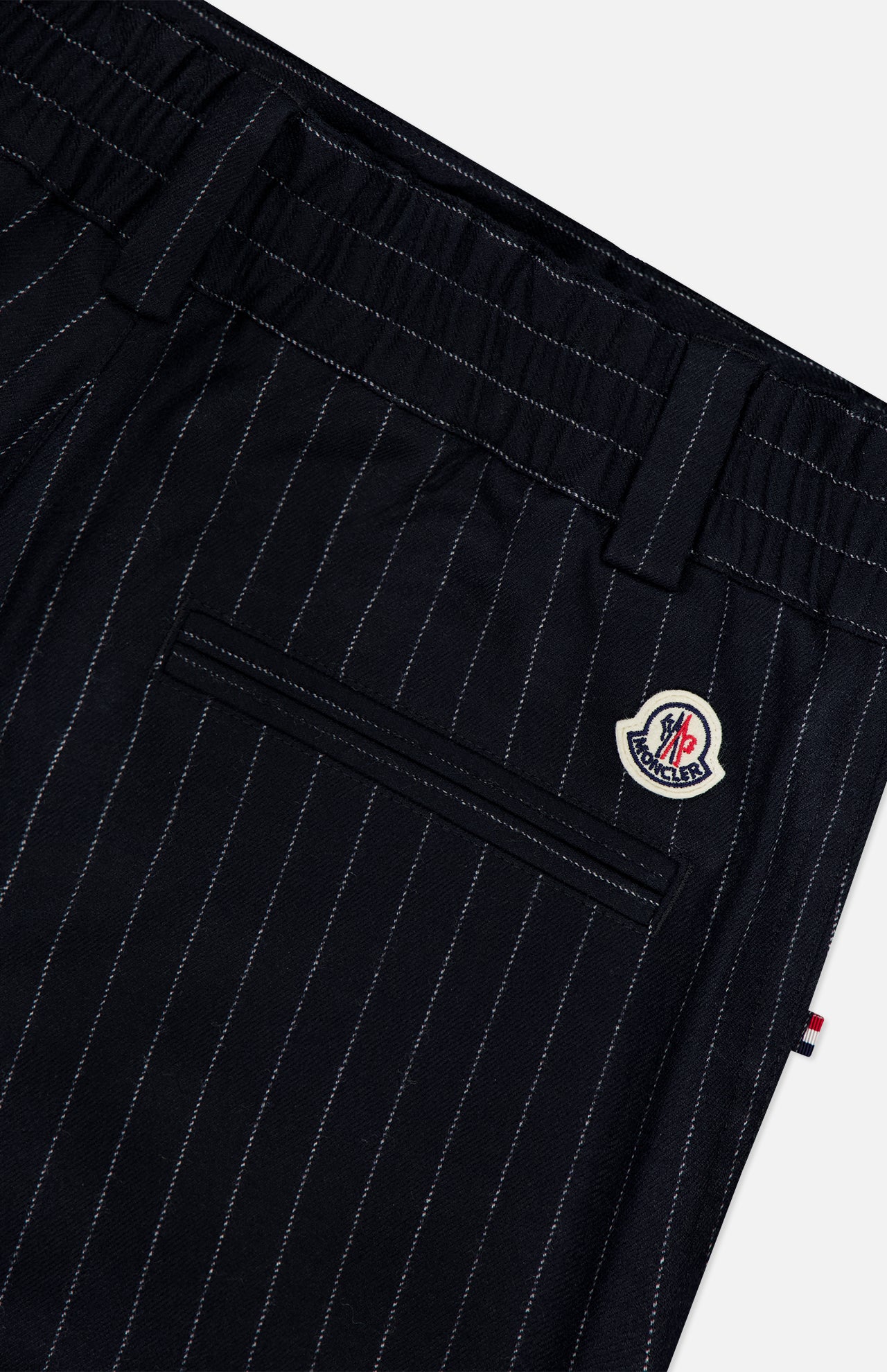 Close-up of MONCLER Striped Drawstring Trousers in dark navy, highlighting a back pocket, belt loops, and a Moncler logo patch above the pocket.