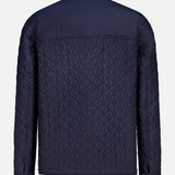 The MONCLER Theoline Quilted Overshirt in navy features a diamond-pattern stitch, long sleeves with buttoned cuffs, and a classic collar—an elegant men's outerwear option shown from the back.