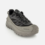 The MONCLER Trailgrip GTX Low Top Sneakers in gray and black feature a chunky Vibram tread outsole and toggle lace system, shown against a plain white background.