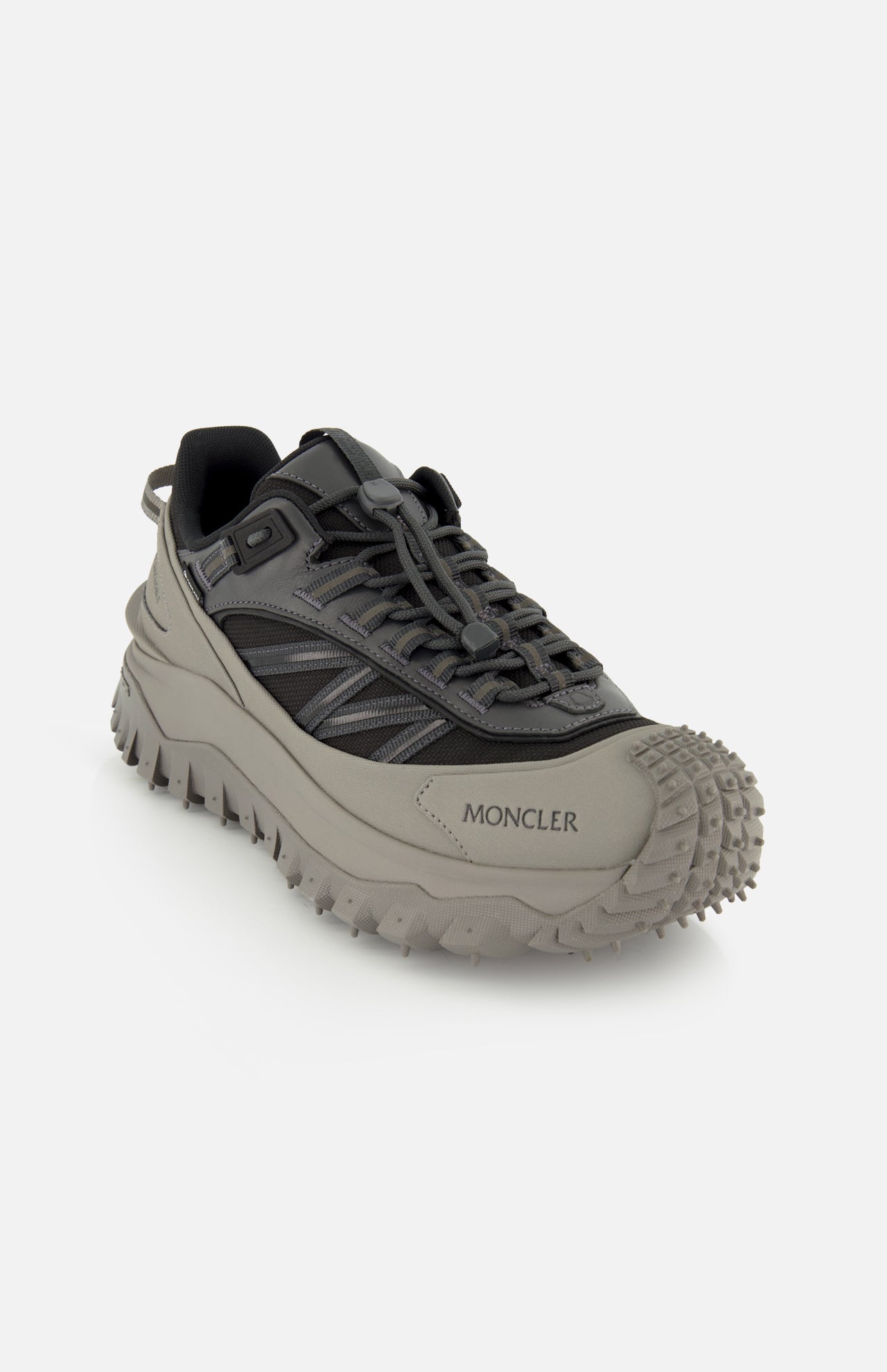 The MONCLER Trailgrip GTX Low Top Sneakers in gray and black feature a chunky Vibram tread outsole and toggle lace system, shown against a plain white background.