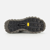 The image shows the bottom view of MONCLER Trailgrip GTX Low Top Sneakers with a rugged black Vibram sole, deep patterned treads for traction, and a yellow logo near the center.