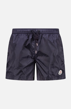MONCLER Swim Shorts in navy blue, featuring an elastic waistband, drawstring front, and a small logo patch on the lower left leg—ideal men's swimwear for stylish beach outings, shown against a plain white background.