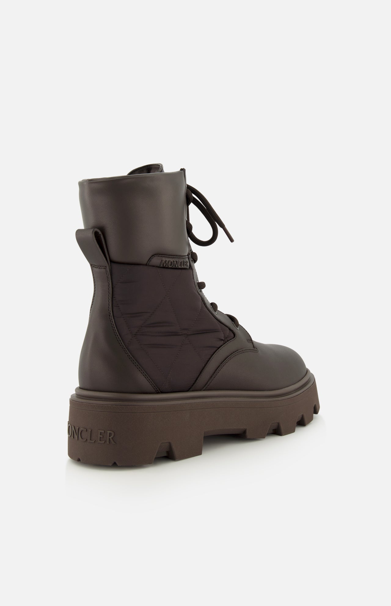 The MONCLER Aurea Quilted Ankle Boots feature dark brown leather and nylon quilted panels, a chunky treaded sole, pull tab at the heel, and embossed logos for a utility-inspired look.