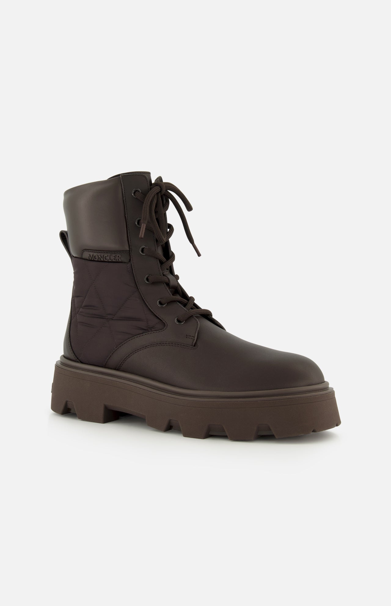 The MONCLER Aurea Quilted Ankle Boots feature a dark brown lace-up design with a thick, rugged sole and stitching details, shown against a plain light background.