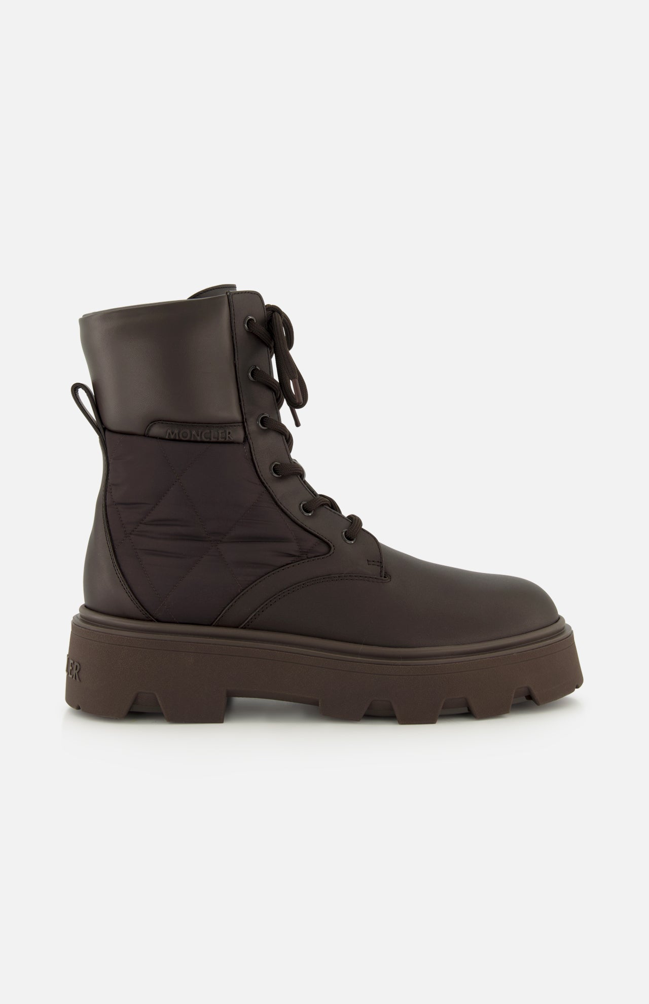 The MONCLER Aurea Quilted Ankle Boots feature dark brown leather and nylon, lace-up front, chunky sole, and quilted side panels for a utility-inspired look, shown against a plain white background.