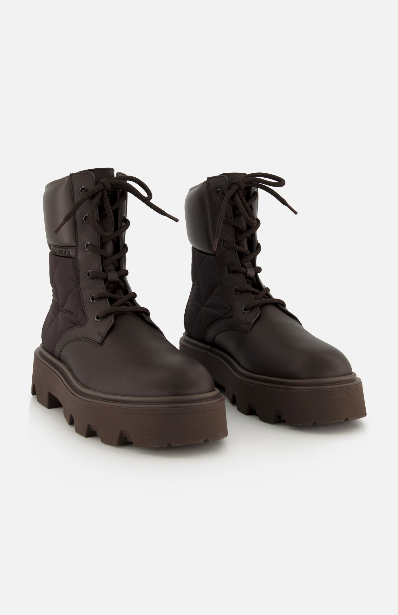 Pair of dark brown Aurea Quilted Ankle Boots by MONCLER, crafted from leather and nylon with a utility-inspired design, lace-up fronts, and thick chunky soles on a plain white background.