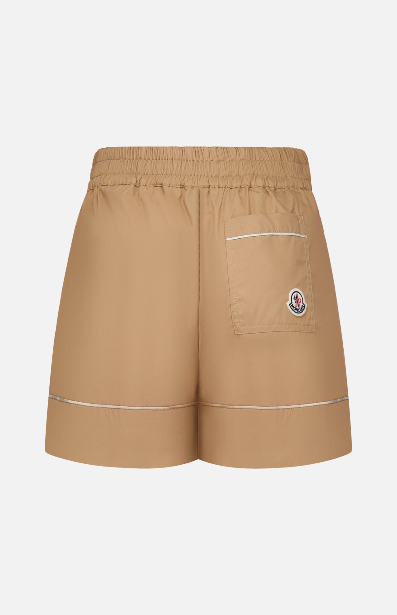 MONCLER Brushed Techno Cotton Shorts in beige feature an elastic waistband, a single back pocket with a logo patch, and white trim on the pocket and hems. Tailored design inspired by Moncler’s high-performance outerwear, shown on a white background.