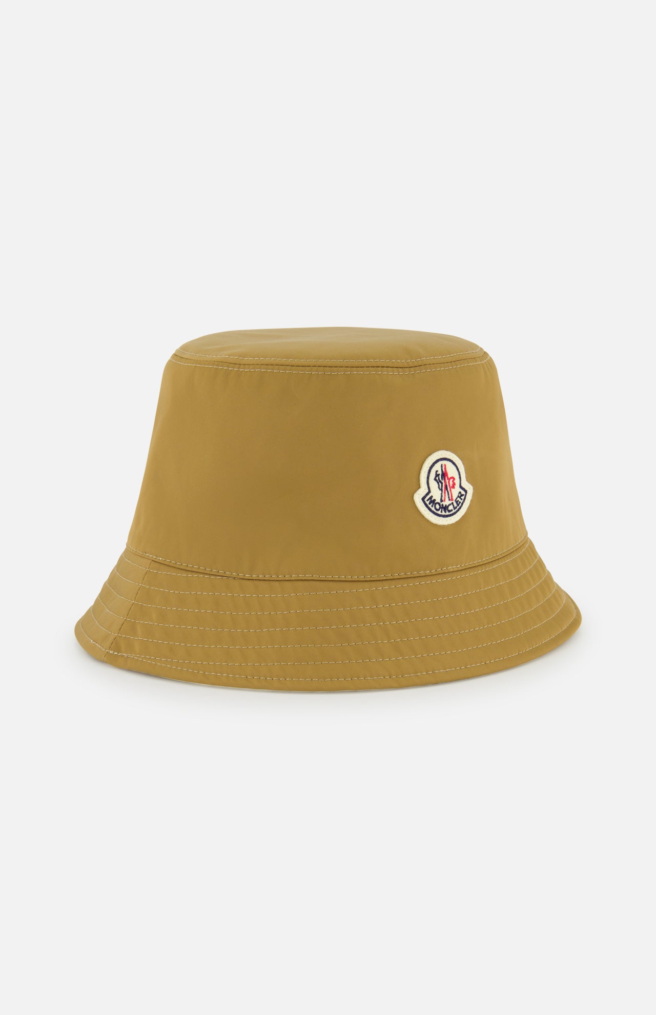 A mustard yellow MONCLER Reversible Bucket Hat with visible stitching and a small embroidered logo patch on the front, shown on a plain white background—blending style and MONCLER's renowned outerwear heritage.