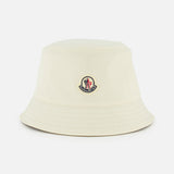 The MONCLER Reversible Bucket Hat in cream features a small front logo patch and is shown on a plain white background—an ideal accessory inspired by the brand's high-performance outerwear.