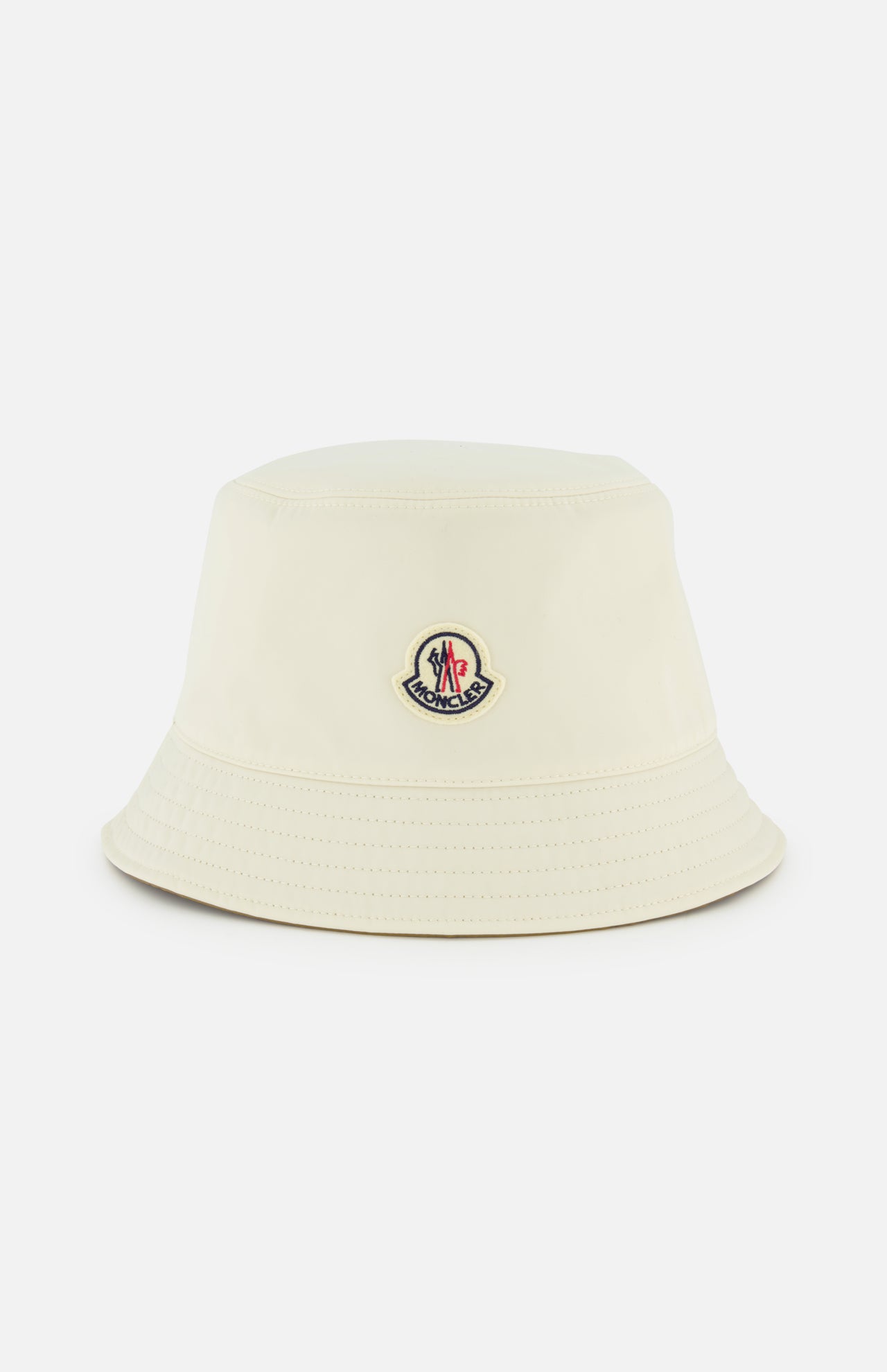 The MONCLER Reversible Bucket Hat in cream features a small front logo patch and is shown on a plain white background—an ideal accessory inspired by the brand's high-performance outerwear.
