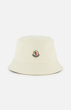 The MONCLER Reversible Bucket Hat in cream features a small front logo patch and is shown on a plain white background—an ideal accessory inspired by the brand's high-performance outerwear.