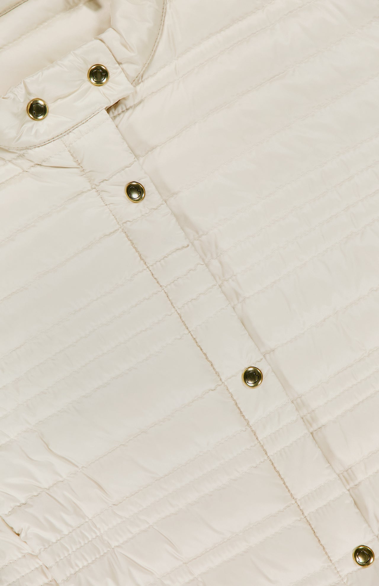 Close-up of a cream-colored quilted fabric from the MONCLER Cataire Quilted Biker Jacket, showcasing horizontal stitching and gold snap buttons on the upper section, highlighting its texture and signature details.