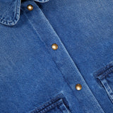 Close-up of a blue MONCLER Denim Vintage Jacket with Removable Collar, featuring metal snap buttons, two chest pockets, and a visible brand label inside the collar—a vintage-inspired outerwear piece.