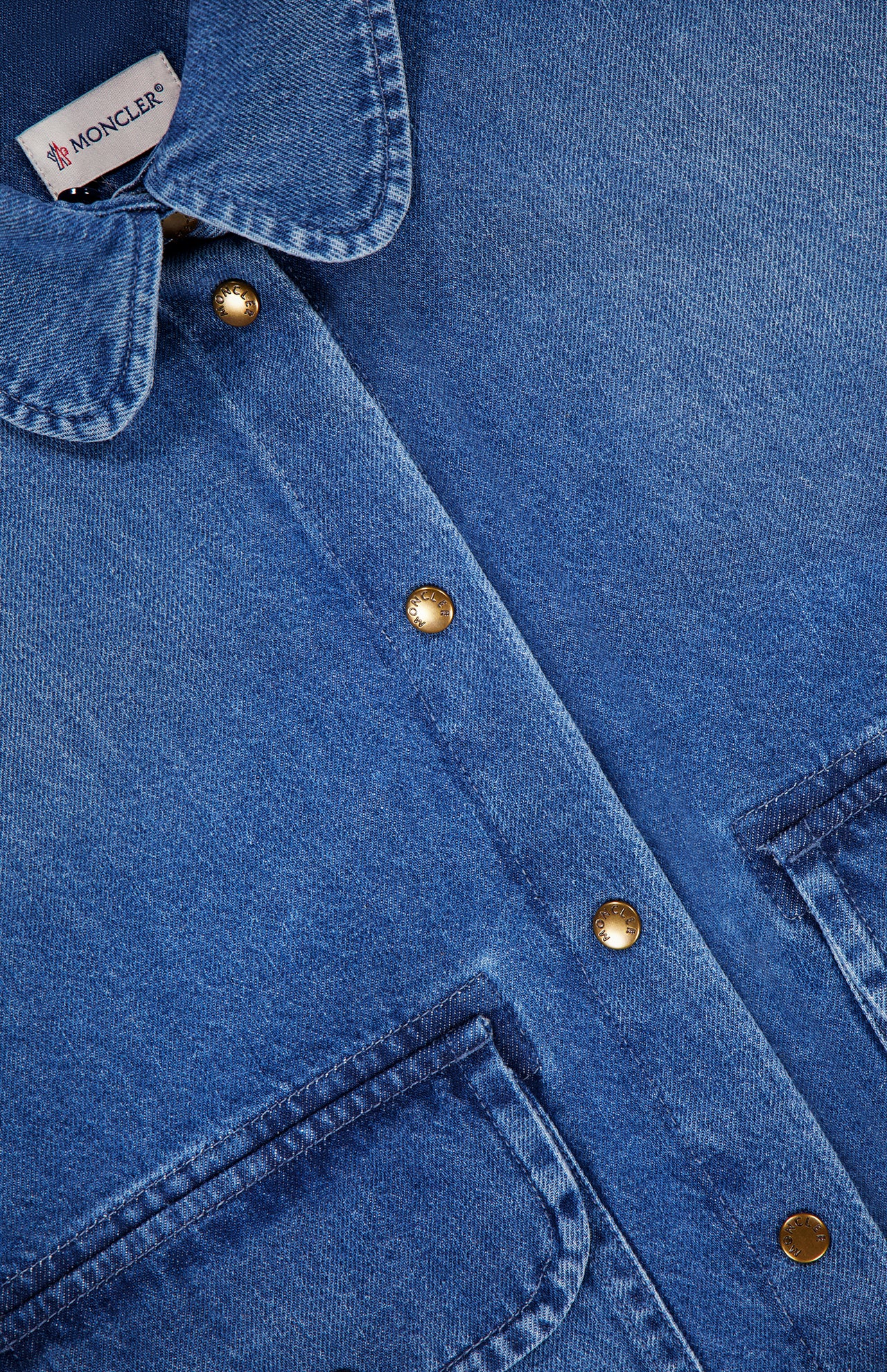 Close-up of a blue MONCLER Denim Vintage Jacket with Removable Collar, featuring metal snap buttons, two chest pockets, and a visible brand label inside the collar—a vintage-inspired outerwear piece.