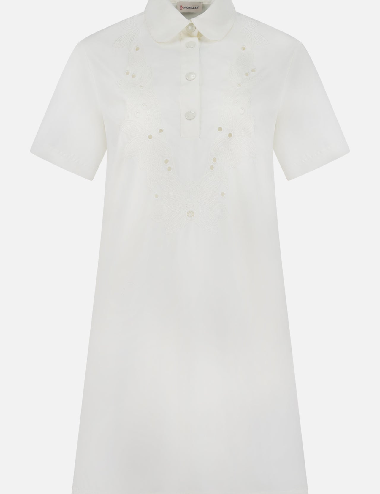 The MONCLER Embroidered Mini Dress is a short-sleeved, knee-length white shirtdress with front buttons, pointed collar, subtle chest floral embroidery, and an elegant A-line silhouette for timeless appeal.