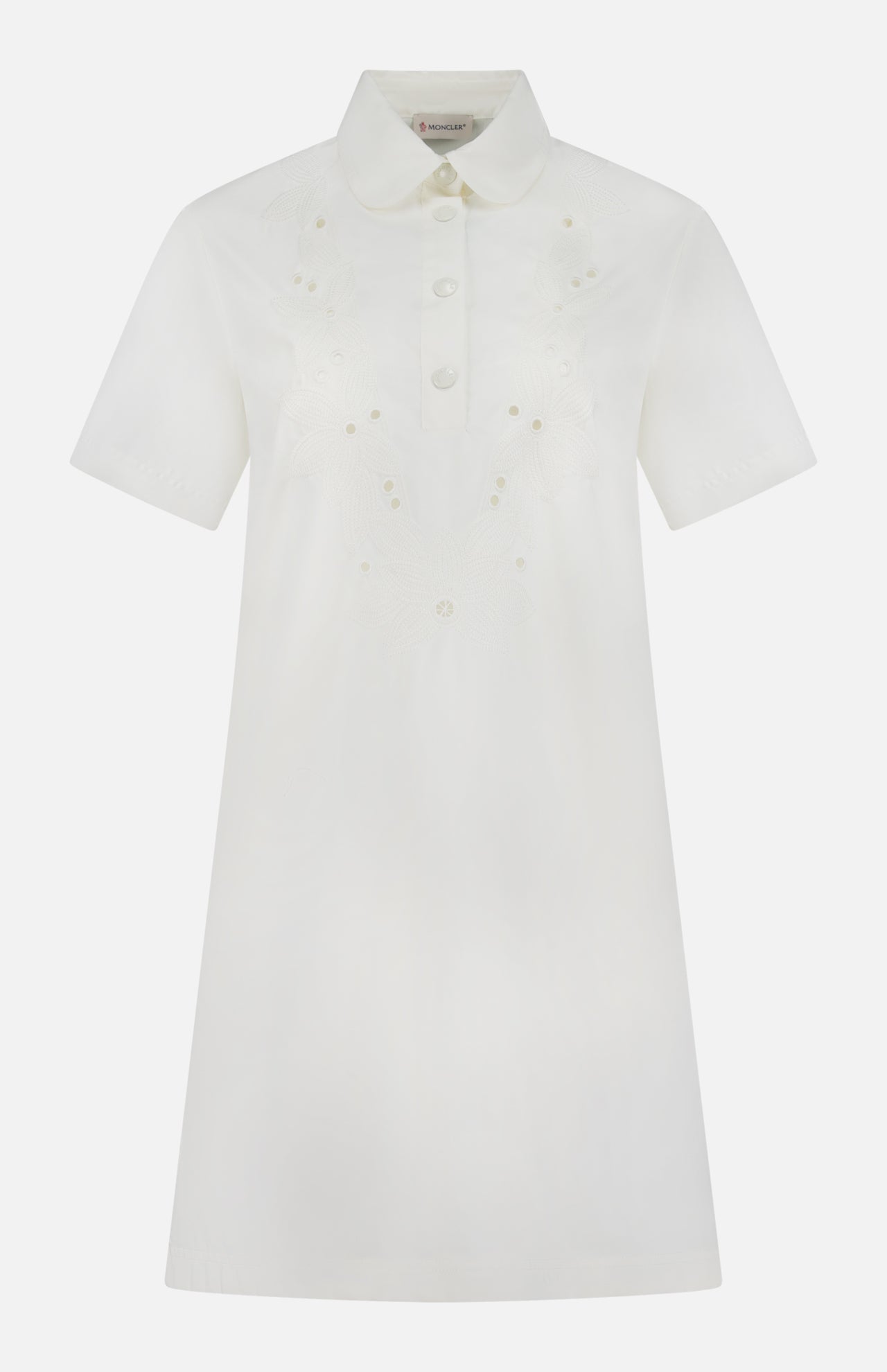 The MONCLER Embroidered Mini Dress is a short-sleeved, knee-length white shirtdress with front buttons, pointed collar, subtle chest floral embroidery, and an elegant A-line silhouette for timeless appeal.
