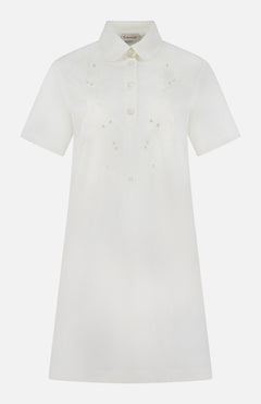 The MONCLER Embroidered Mini Dress is a short-sleeved, knee-length white shirtdress with front buttons, pointed collar, subtle chest floral embroidery, and an elegant A-line silhouette for timeless appeal.