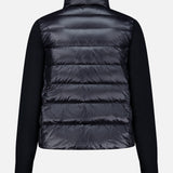 A black Extrafine Wool Cardigan by MONCLER, featuring a shiny, quilted puffer back panel and matte long sleeves, is shown from the back against a plain white background.