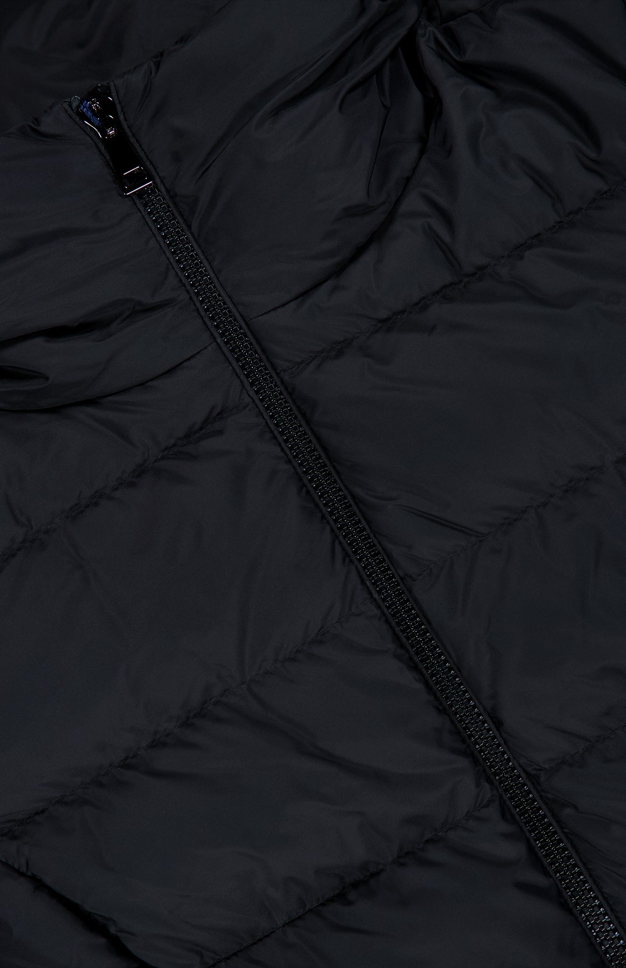 Close-up of the black quilted fabric and diagonal zipper from the MONCLER Gie Concealed Hood Long Coat, highlighting the water-repellent material’s texture and stitching.