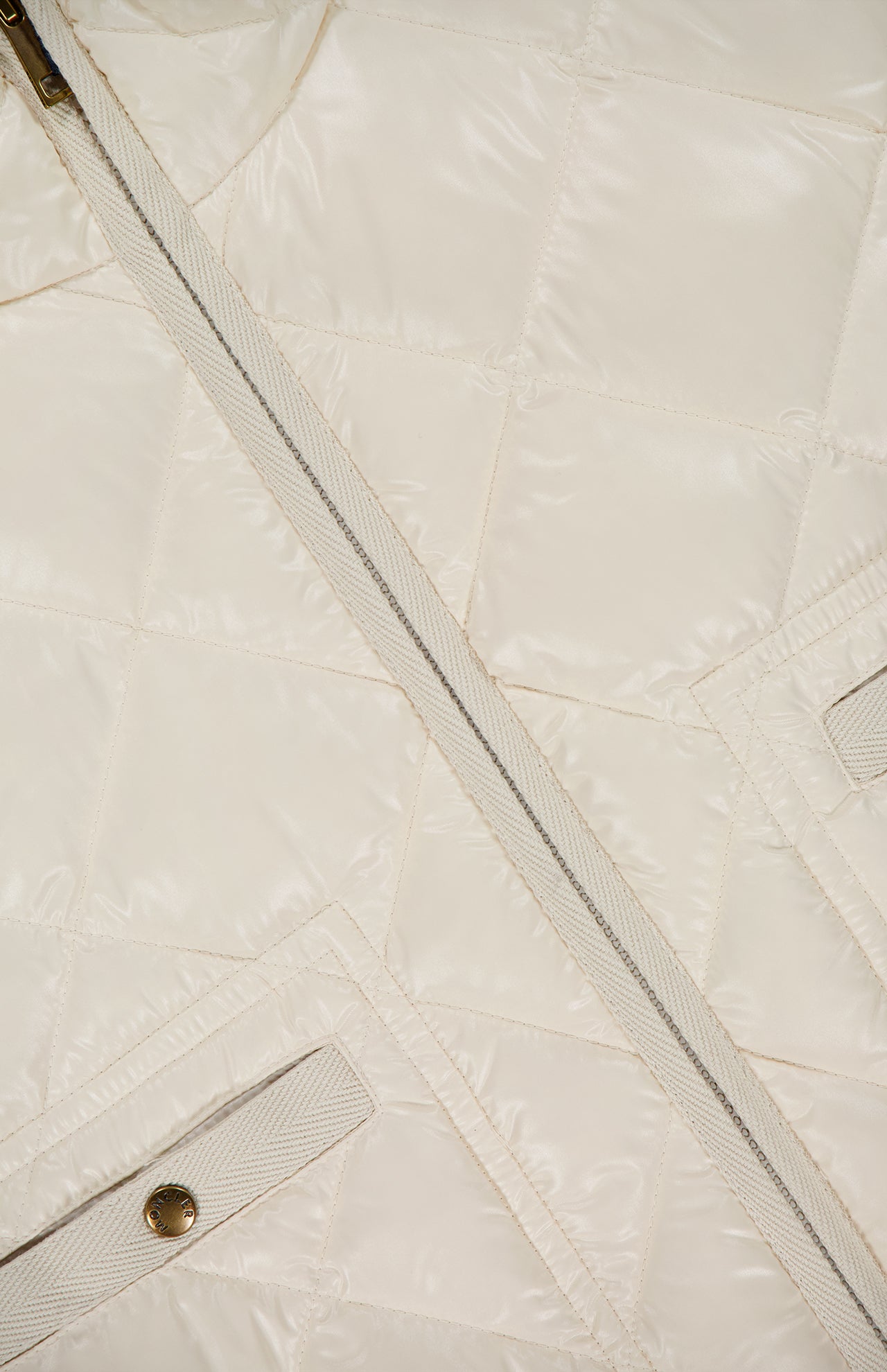 Close-up of the MONCLER Lavaret Quilted Puffer Jacket in cream, showcasing its classic quilted texture, diagonal zipper, and button-flap pocket. Lightweight design highlights signature stitching inspired by Moncler’s iconic puffer styles.