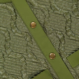 Close-up of quilted olive green fabric from the MONCLER Libellule Water Repellent Quilted Jacket, featuring textured stitching, gold snap buttons, and smooth trim that highlight this feminine puffer down jacket’s luxurious details.