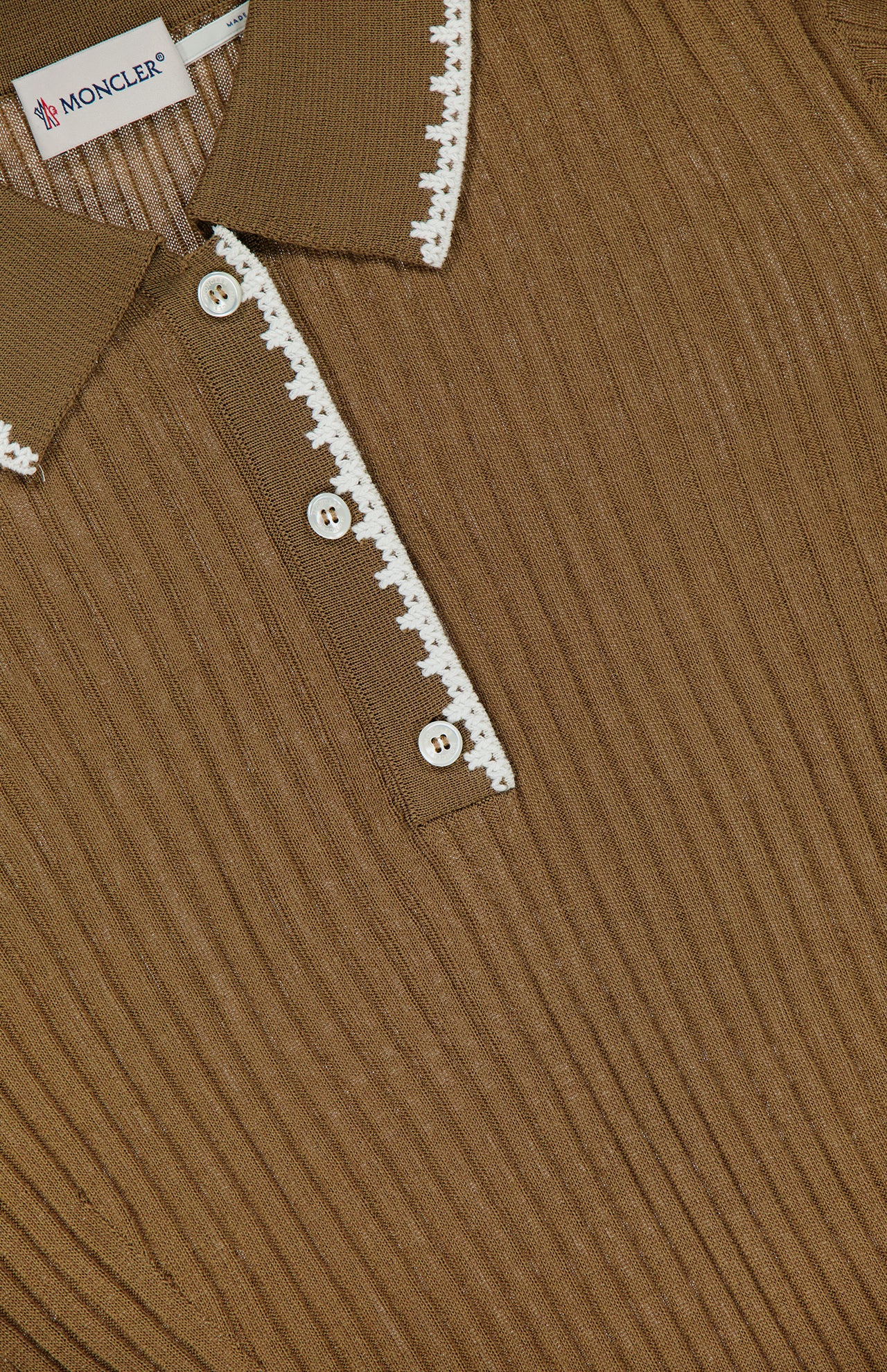 Close-up of the MONCLER Long Sleeve Stitched Polo, crafted in ribbed brown fabric with a collar and white crochet trim on the placket, three white buttons, and the MONCLER label visible inside the collar.