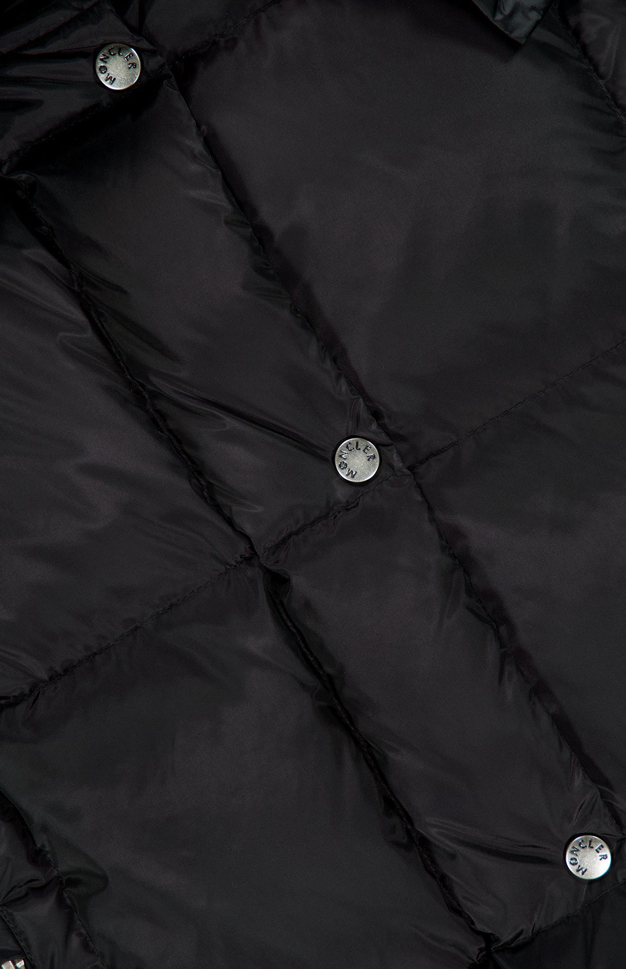 Close-up of the MONCLER Macareux Down Puffer Vest in black, showcasing its glossy quilted fabric and multiple metallic snap buttons embossed with text—an elegant example of water-repellent outerwear that blends style with functionality.