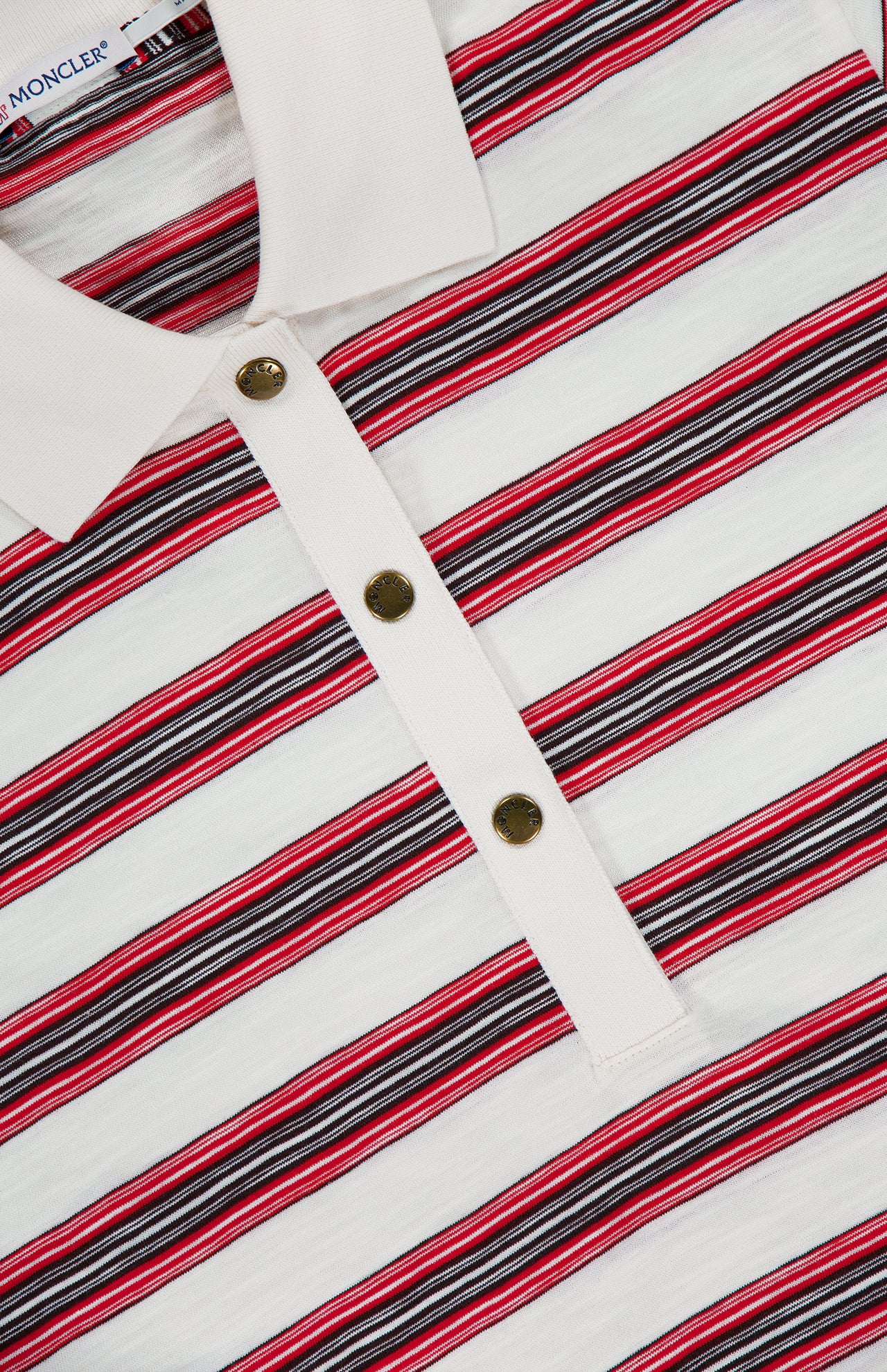 Close-up of the MONCLER Striped Short Sleeve Polo—a white polo shirt with red, black, and gray horizontal stripes—showcasing a white placket with three metal buttons and part of the collar in view. Perfect for men's casual wear.