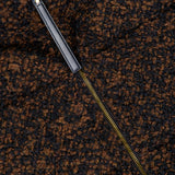 A close-up of the brown and black textured wool fabric of the MONCLER Trascendance Tweed Jacket, showcasing a partially unzipped gold zipper with a black leather pull tab—an elegant detail characteristic of this sophisticated piece.