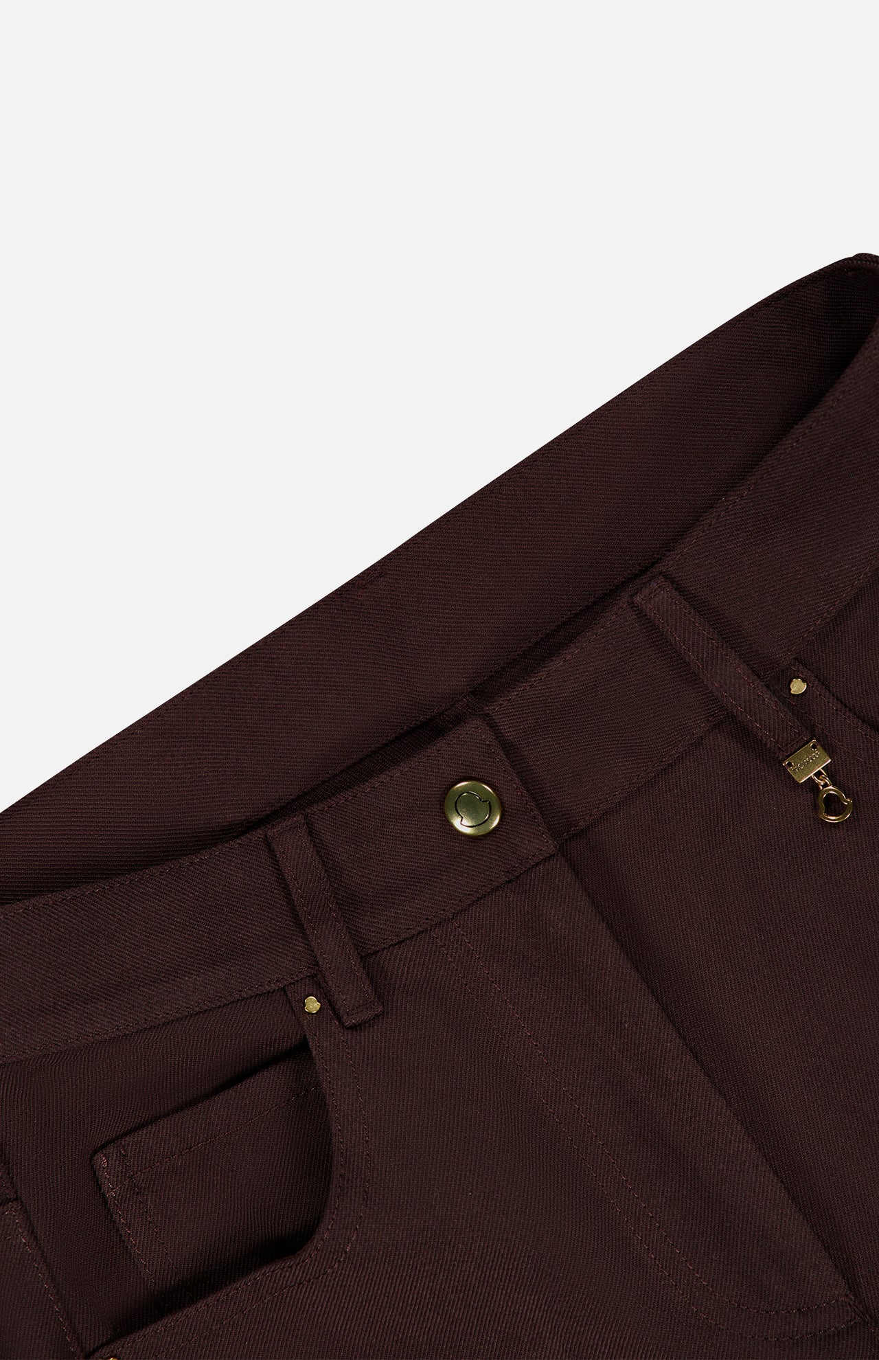 Close-up of the waistband and zipper area of MONCLER Straight Leg Trouser Pants in dark brown, featuring a brass button and zipper, visible belt loops, and pocket seams against a plain light gray background.