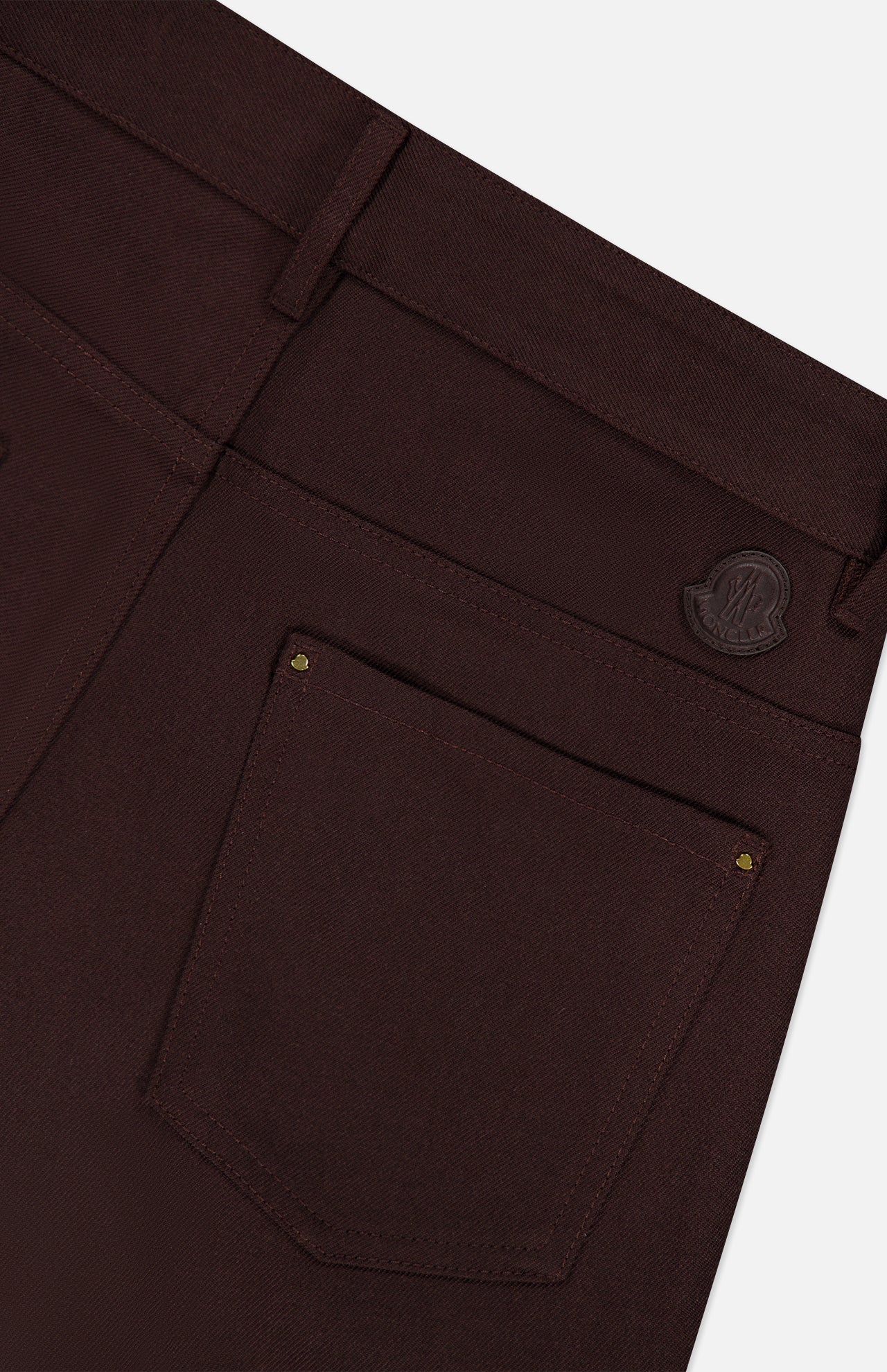 Close-up of the back pocket of MONCLER Straight Leg Trouser Pants in dark brown, featuring a small leather patch above the pocket and gold rivets on the corners.