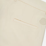 Close-up of the back of cream-colored MONCLER Wide Leg Trousers, showing a single welt pocket, belt loops, and a small circular beige logo patch near the waistband.