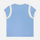 The Boxy Goodie Inset T-shirt by MOTHER, shown laid flat with its back facing up, features light blue 100% cotton fabric and white trim on the sleeves and neckline.