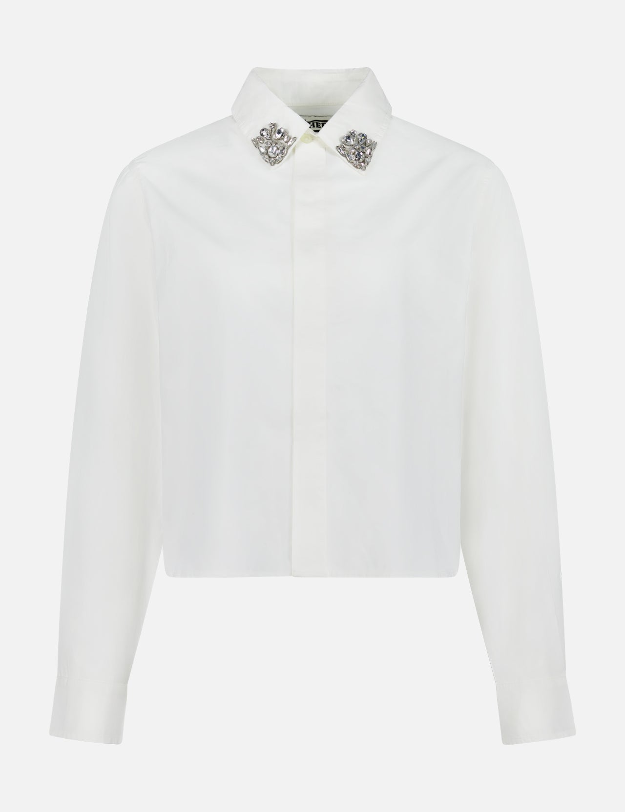 The Honor Embellished Collar Shirt by MOTHER is a cropped, white 100% cotton button-up with a pointed collar adorned with silver tips and a clean, tailored front with no visible buttons.