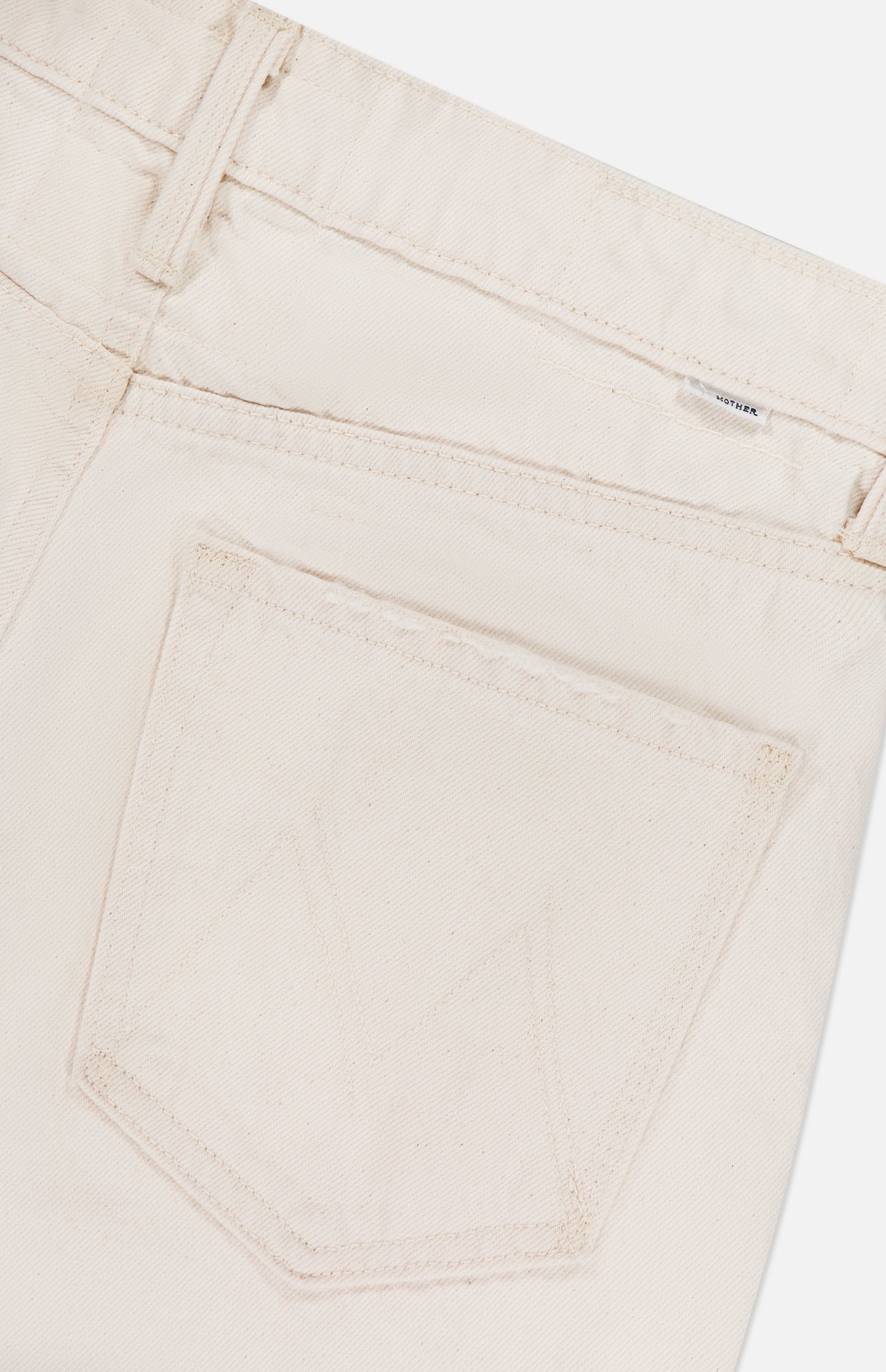 Close-up of the back pocket on MOTHER's The Scooter Skimp Flare Leg Pant in off-white, highlighting visible stitching and part of the waistband with a belt loop.