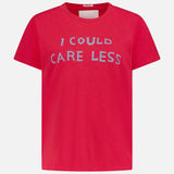 The Sinful Slim T-shirt by MOTHER is a bright pink vintage-style short-sleeve tee with "I COULD CARE LESS" in bold light blue letters on the chest, shown against a plain light gray background.