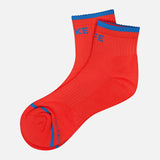 A pair of MOTHER Baby Steps Ankle Socks in bright red with blue accents on the toe, heel, and cuff, featuring bold blue text near the toe and ankle, shown against a plain white background.