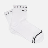 A pair of MOTHER Baby Steps Ankle Socks with Studs in a white cotton-blend, featuring black smiley face designs around the top edge and black text partially visible on the cuff and toe—perfect for making a subtle statement with your socks.
