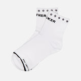 The Baby Steps Ankle Socks with Studs by MOTHER are white cotton-blend ankle socks featuring black text and smiley faces along the cuff. Additional black text decorates the toe area, adding a playful touch to these statement socks. They are shown laid flat on a white background.