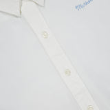 Close-up of The Bestie Button-front Shirt by MOTHER, a 100% cotton white shirt featuring cream-colored buttons and "Mother" embroidered in light blue on the chest.