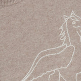 A close-up of The Biggie Pegasus Jumper Sweater by MOTHER showcases its beige knit fabric, adorned with a partial white outline drawing of a winged horse. A brown collar tag displays the brand name, MOTHER, in yellow letters.