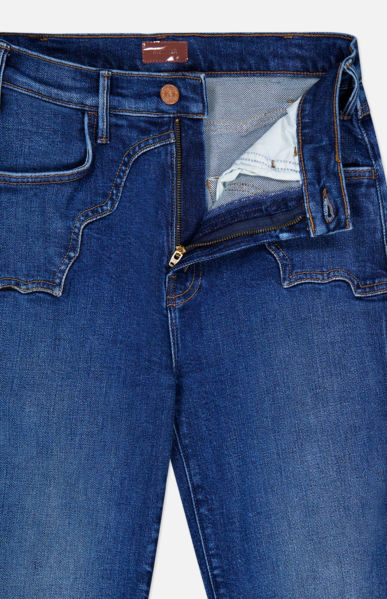 The Buckle Bunny Hustler Jean in Cosmic Cowgirl by MOTHER features dark blue stretch denim with a brass button and a partially open zipper fly that reveals the inner pocket lining. These high-rise flare jeans showcase visible stitching and uniquely curved front pockets, adding a subtle western-inspired detail.