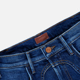 Close-up of the waistband and upper part of The Buckle Bunny Hustler Jean in Cosmic Cowgirl by MOTHER, featuring a brown button, belt loops, front pockets, and a leather patch on the inside of the waistband.