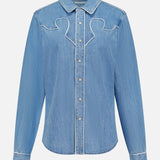 The Country Exe’s Shirt by MOTHER is an oversized, light blue denim shirt featuring long sleeves, a pointed collar, snap button closure, and white stitched decorative details along the chest and seams. Displayed on a plain white background, this classic western button-up brings timeless charm to any wardrobe.