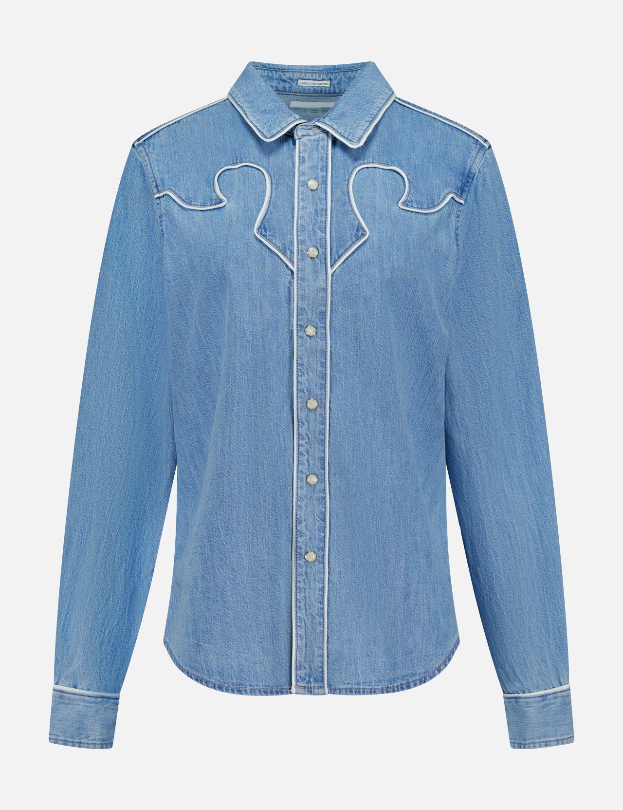 The Country Exe’s Shirt by MOTHER is an oversized, light blue denim shirt featuring long sleeves, a pointed collar, snap button closure, and white stitched decorative details along the chest and seams. Displayed on a plain white background, this classic western button-up brings timeless charm to any wardrobe.
