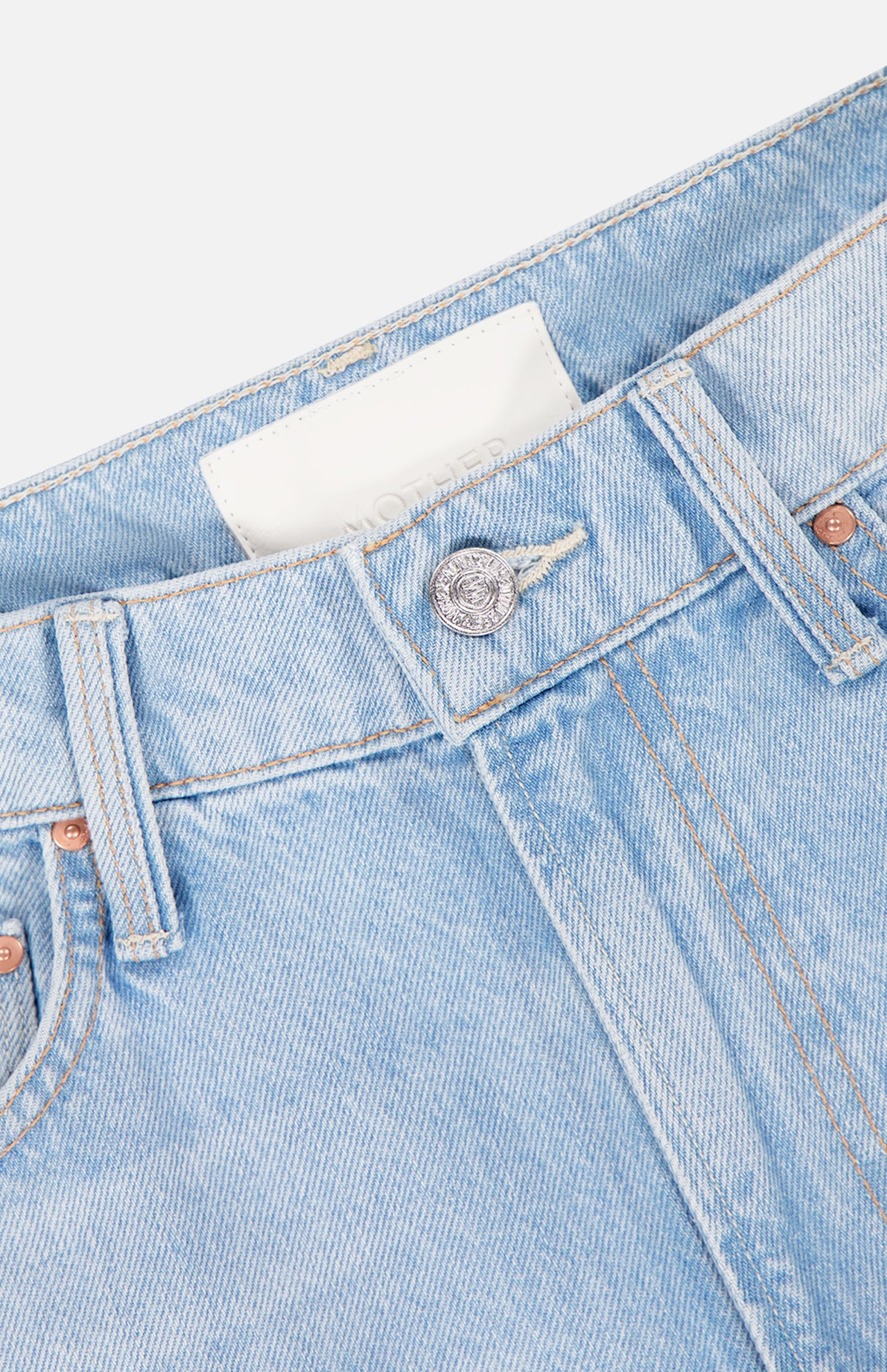 Close-up of the waistband and upper section of MOTHER's The Ditcher Roller Jeans in Few & Far Between, featuring button closure, belt loops, stitching details, and a glimpse of a white label inside.